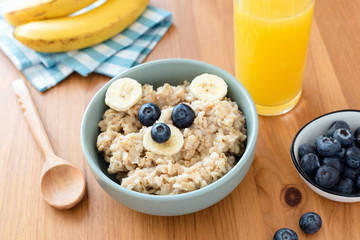 Oatmeal porridge with funny bear animal face, glass of orange juice. Healthy breakfast for kids