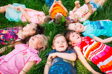 A group of children lying on the green grass in the Park. The interaction of the children.
