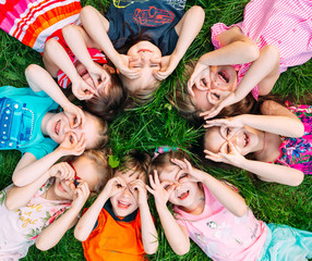 A group of children lying on the green grass in the Park. The interaction of the children.