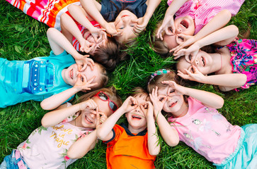 A group of children lying on the green grass in the Park. The interaction of the children.