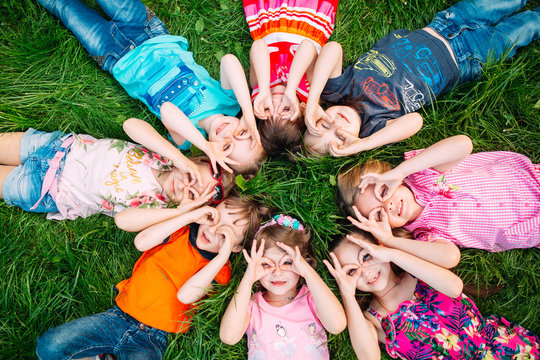 A group of children lying on the green grass in the Park. The interaction of the children.