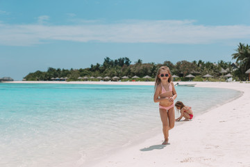 Two little happy girls have a lot of fun at tropical beach playing together