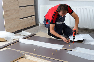 Close-up of the process of installation a furniture. Man's hands working with a screwdriver.