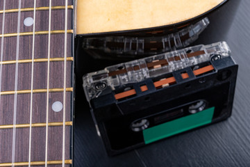 Acoustic guitar and cassette tape. Musical instrument and old music carrier.