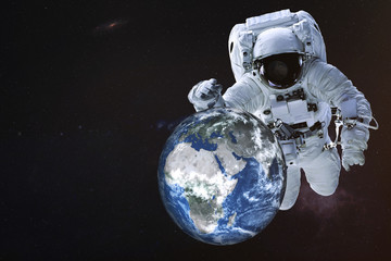 Fototapeta na wymiar Giant Astronaut near the Earth planet of Solar system near his hand and reflection on helmet. Science fiction. Elements of the image are furnished by NASA
