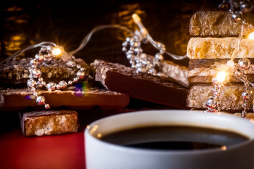 Obraz na płótnie Canvas Cup of coffee and turron. Selective focus. Blurred background. Traditional Spanish Christmas candy. Christmas lights and tree decorations in the background.