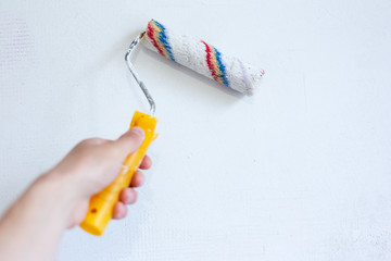 Close-up of paint roller on white wall background