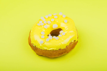 Donut with white glaze on a yellow background