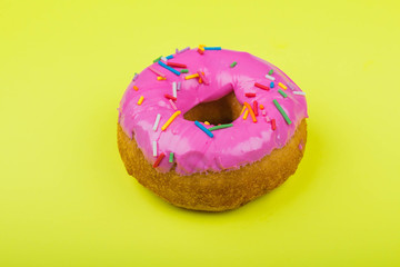 Donut with pink glaze on a yellow background