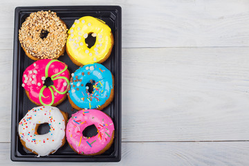 donuts with glaze in a box on a white wooden background
