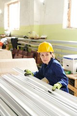 High angle portrait of adult woman wearing hardhat working at metal production factory, copy space