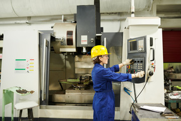 Side view portrait of female worker operating machine units at factory, copy space