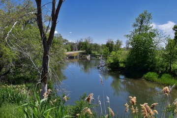 Jordan River Parkway Trail, Redwood Trailhead bordering the Legacy Parkway Trail, panorama views with surrounding trees and silt filled muddy water along the Rocky Mountains, Salt Lake City, Utah. 