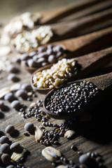 wooden spoons with cereals and seeds on wooden background