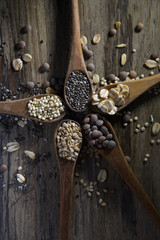Fototapeta na wymiar wooden spoons with cereals and seeds on wooden background