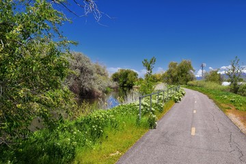 Jordan River Parkway Trail, Redwood Trailhead bordering the Legacy Parkway Trail, panorama views with surrounding trees and silt filled muddy water along the Rocky Mountains, Salt Lake City, Utah. 