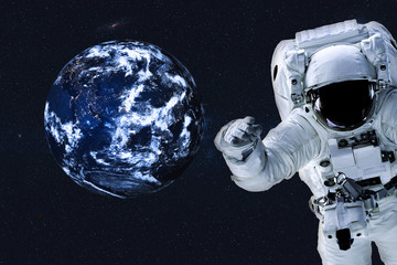 Fototapeta na wymiar Astronaut near the Earth planet at night with city lights of Solar system. Science fiction. Elements of the image are furnished by NASA