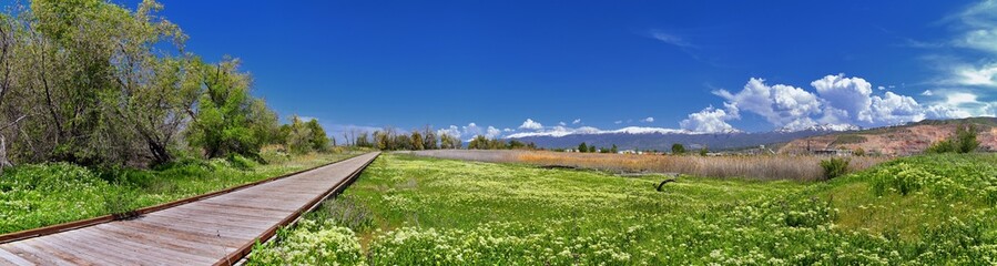 Jordan River Parkway Trail, Redwood Trailhead bordering the Legacy Parkway Trail, panorama views with surrounding trees and silt filled muddy water along the Rocky Mountains, Salt Lake City, Utah. 