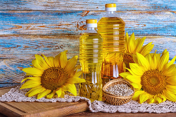 Rural still-life - sunflower oil in bottles with flowers of sunflower (Helianthus annuus), closeup