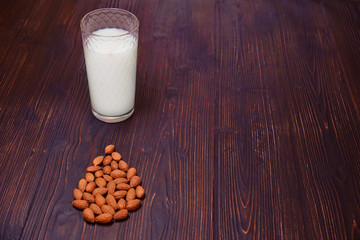 Fresh squeezed diet drink. Almond milk and nuts on red wooden background, copy space. Organic milk of vegetable origin.