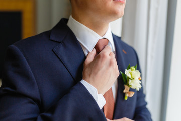 Elegant businessman sewed to order suit, straightens his tie in an expensive hotel, going to a meeting