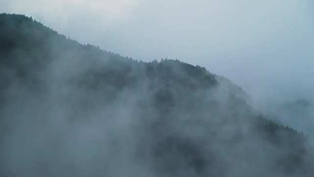moody clouds and fog roll over green mountain tops on a rainy day in tropical mountains