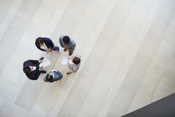 Directly above view of busy creative business colleagues in formal outfits standing in circle and...