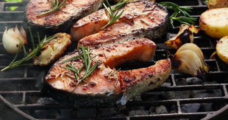 Grilled fish, grilled salmon steak with the addition of rosemary, aromatic spices and vegetables on the grill plate outdoors,  close-up, 4k. Grilled seafood