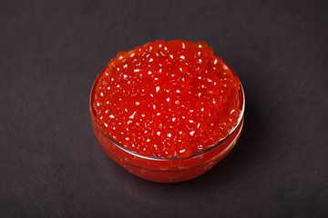 red caviar in glass bowl on black background