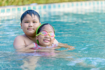 Fototapeta na wymiar Happy brother and sister playing in swimming pool,