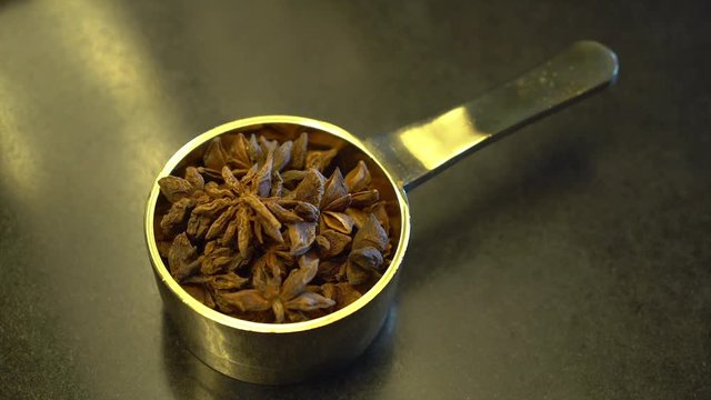 A steady, close up shot of a tiny metal bowl filled with dry anason.