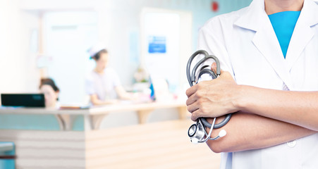 Double exposure of Doctor with stethoscope on blurred hospital background.