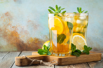 Traditional iced tea with lemon and ice in tall glasses on a wooden rustic table. With copy space