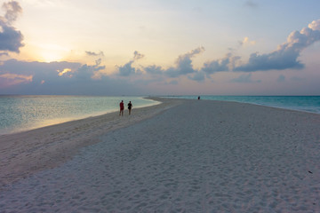 A couple of lover walking on sand bank beach in Maldives at sunset