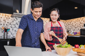 Asian senior couple enjoy cooking in kitchen at home