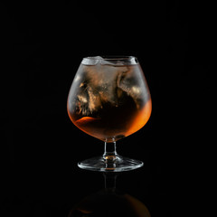 Close-up brandy glass filled with whiskey with ice.