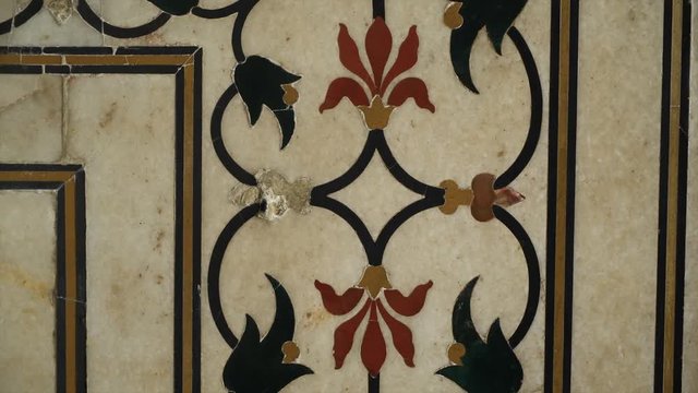 A hand held, close up shot of red, green and yellow floral motifs on a wall.