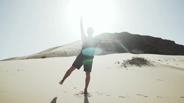 Handsome male doing yoga tadasana pose on a sand dune in desert 4k