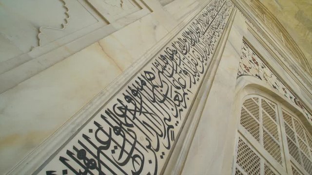 A hand held, high angle, close up shot of Arabic engravings at the entrance to the temple.