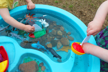 Children Playing with Boats and Sea Creature/Ocean Life Toys in a Water Table. Science/STEM activity being enjoyed by children in a daycare/child care/home school setting.