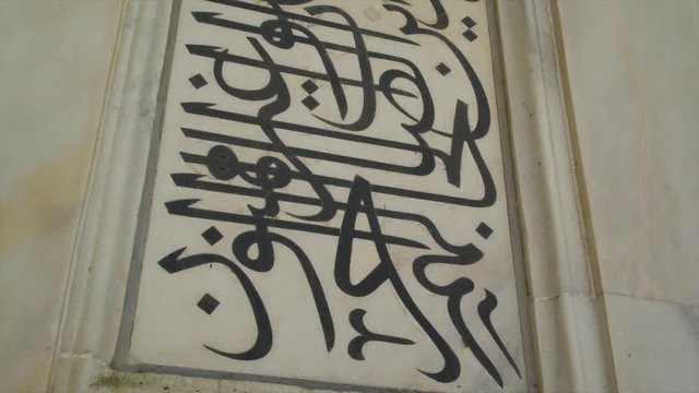 A hand held, extreme close up shot of some black writings on the wall.