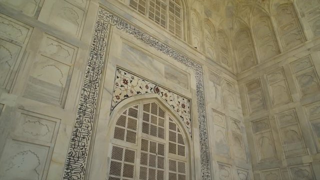 A hand held, high angle, wide shot of high white walls and old decorations.