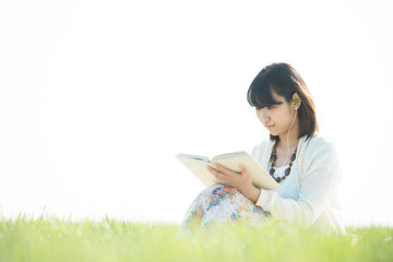 草原で音楽を聴きながら本を読む女性