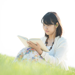 草原で音楽を聴きながら本を読む女性
