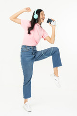 Happy asian teen passenger listening to the music with headphones while holding  mobile phone.businesswoman listening to music with headphones while dancing isolated over white background