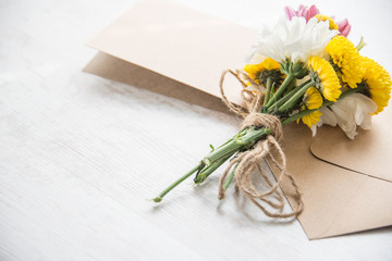 Flowers bouquet with card note and envelope on a white wood rustic background