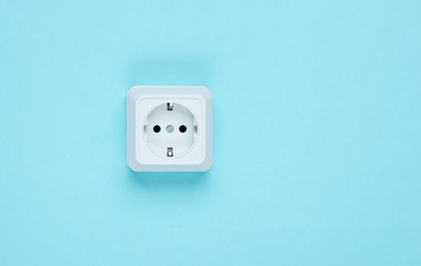 White plastic power socket on blue background. Wall with copy space. Minimalism