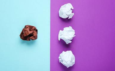 The concept of uniqueness, racial discrimination. White and brown crumpled paper balls on purple...