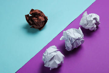 The concept of uniqueness, racial discrimination. White and brown crumpled paper balls on purple blue background. Minimalism business
