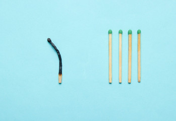 Burned and whole matches on a blue background. Minimalism concept